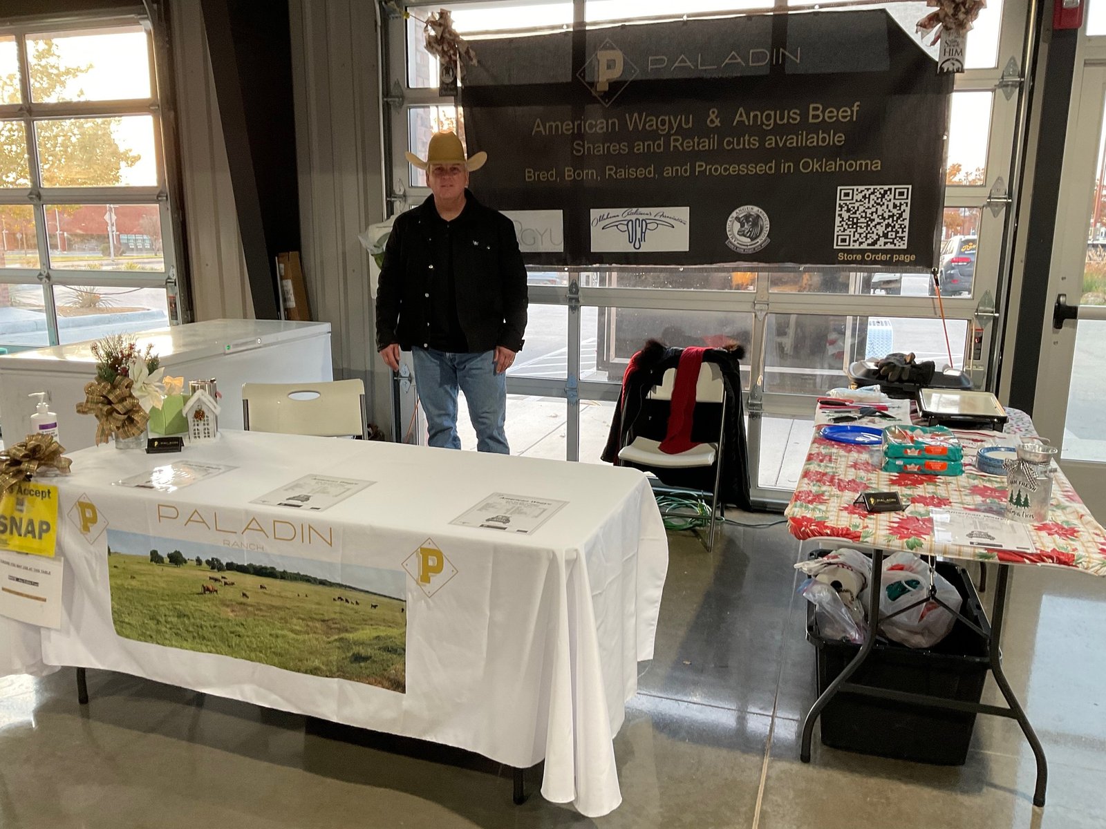 The Paladin Ranch farmers market booth with banner, samples, and the family behind the table