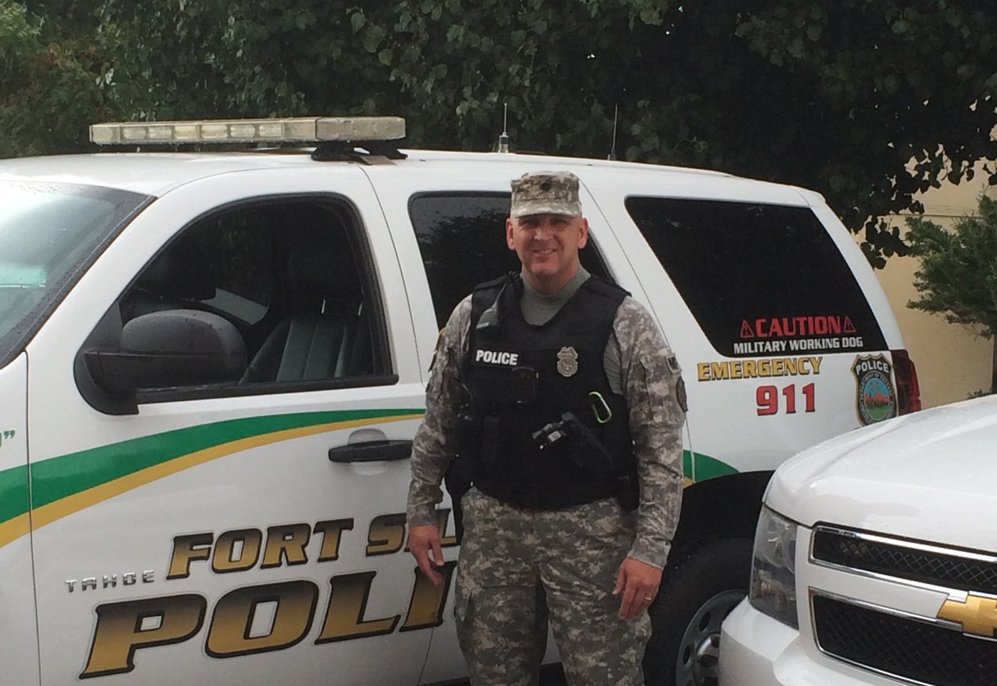 Then-Lieutenant Colonel Spivey in a police vest beside a Fort Sill Police vehicle